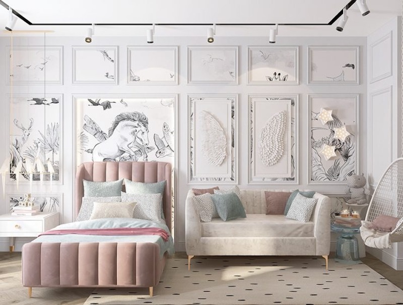 Giường bọc nệm hồng phấn dáng gọn đặt trước mảng tường phào chỉ trắng tinh tế, điểm tranh vẽ nhẹ nhàng, tạo không gian vừa thanh lịch vừa giàu chất mơ mộng