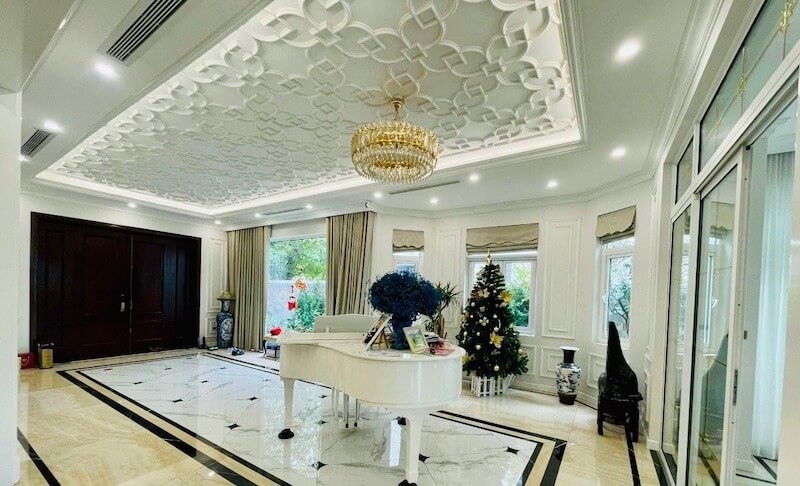 Sự giao thoa nghệ thuật giữa đàn piano trắng tinh khôi và trần hoa văn tinh xảo, tạo điểm nhấn lãng mạn, thanh lịch trong không gian Tân cổ điển