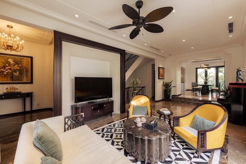 Tinh thần Indochine thể hiện qua quạt trần cánh lá, nội thất gỗ tối màu và họa tiết gạch bông đặc trưng, tạo không gian hoài cổ, tinh tế