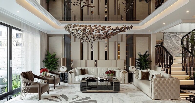 Phòng khách thông tầng sang trọng với sofa bọc da kem, bàn trà đen bóng, đèn chùm nghệ thuật, vách ốp kim loại, tạo cảm giác đẳng cấp, bề thế, tinh tế, ấm cúng