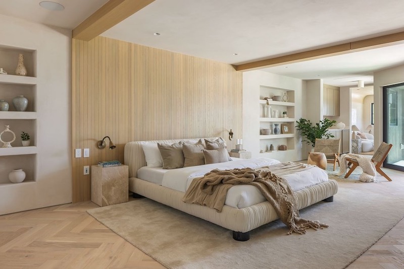 Giường bọc nỉ bo tròn tạo cảm giác thư giãn, mảng ốp gỗ đầu giường giữ ấm thị giác, kệ âm tường trưng bày tinh gọn, tăng tính nghỉ dưỡng