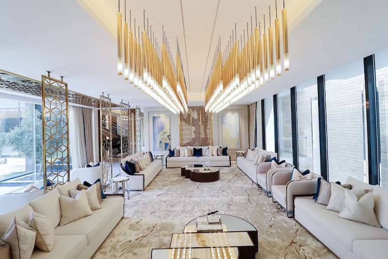 Hệ đèn thả kim loại thiết kế riêng tạo trục thị giác độc bản, sofa đối xứng may đo theo không gian, thảm đá vân tự nhiên và vách trang trí thủ công khẳng định dấu ấn Bespoke cá nhân hoá