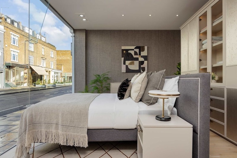 Giường bọc nỉ đặt riêng kết hợp tab đầu giường tối giản viền kim loại, tranh trừu tượng treo độc bản và hệ tủ âm đo ni đóng giày, tạo cảm giác sang trọng tinh tế