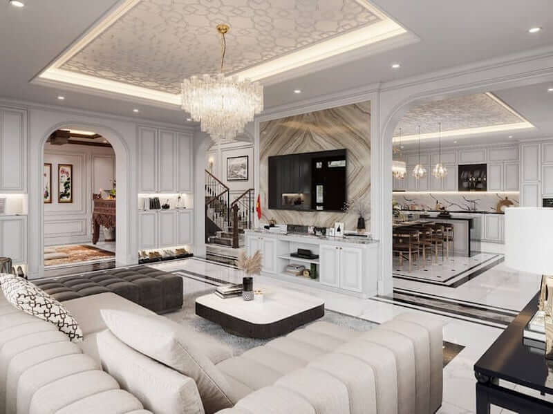 Phòng khách toát lên vẻ sang trọng nhờ phào chỉ đối xứng, đèn chùm pha lê rực sáng, mảng đá marble vân mây, sofa tông kem, bố cục liên thông tinh tế