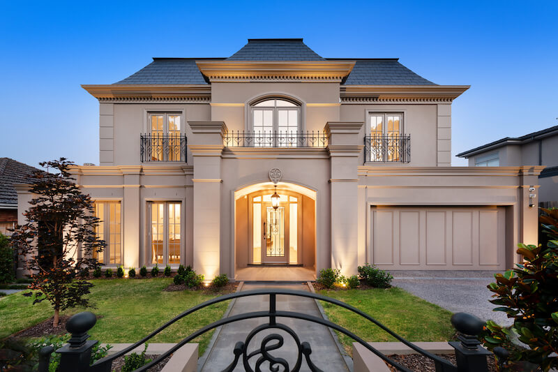 Sân vườn gọn gàng với thảm cỏ xanh mướt, lối đi lát đá thẳng trục trung tâm và hệ cây bụi cắt tỉa chỉn chu, tạo cảm giác thanh lịch, cân đối