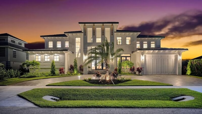 Thảm cỏ xanh mịn, bố cục uốn lượn mềm mại quanh lối xe vào và điểm nhấn là cây cọ trung tâm kết hợp hệ cây bụi thấp