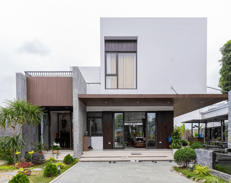 Khoảng sân trước lát đá rộng rãi cùng tiểu cảnh cây xanh giúp mặt tiền trở nên sinh động, đồng thời tạo khoảng đệm thư giãn trước khi bước vào không gian bên trong