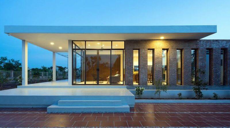 Mặt tiền kết hợp tường gạch mộc và hệ cửa kính lớn, tạo điểm nhấn ấm áp và giúp không gian bên trong luôn thoáng sáng