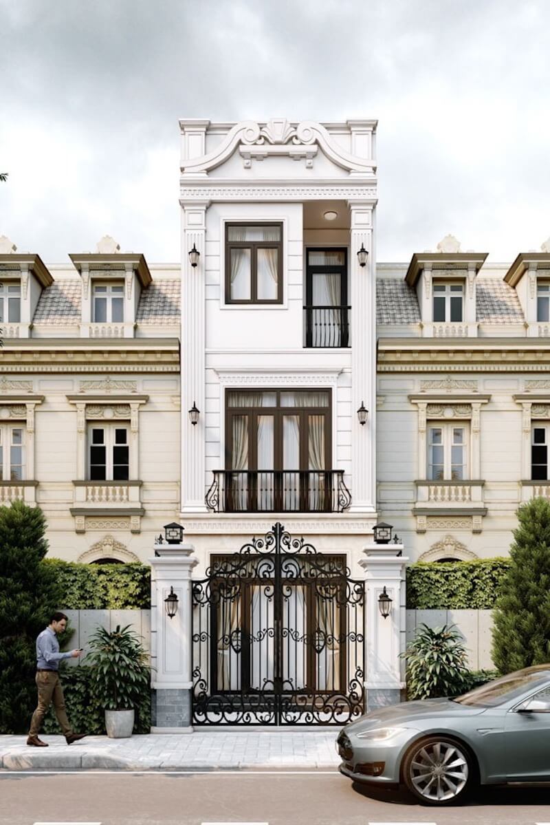 Cổng rào sắt hoa văn và mảng xanh tiền cảnh giúp công trình giữ được vẻ sang trọng kín đáo, đồng thời tách biệt nhịp sống bên trong khỏi không gian phố xá bên ngoài