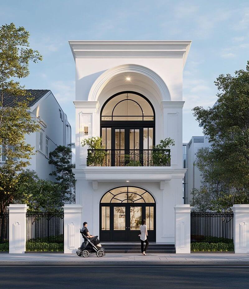 Gam trắng chủ đạo kết hợp khung cửa sắt đen và kính lớn giúp công trình vừa giữ được tinh thần cổ điển, vừa đáp ứng nhu cầu ánh sáng và sự thông thoáng của nhà phố