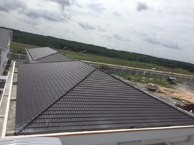 Hệ mái bê tông dán ngói xám hiện đại với đường xối giữa và đường viền trắng tinh tế, mang lại khả năng chống nóng và thoát nước tối ưu cho ngôi nhà