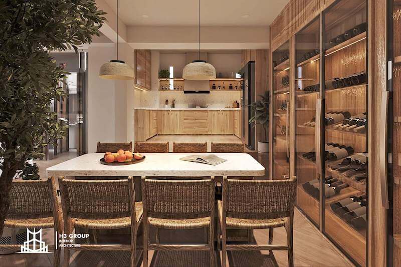 Khu bếp nổi bật với hệ tủ gỗ sáng tự nhiên kết hợp mặt đá trắng, đèn thả mây tre và bàn ăn ghế đan mộc mạc, tạo cảm giác ấm áp, gần gũi nhưng vẫn tối giản và tinh tế