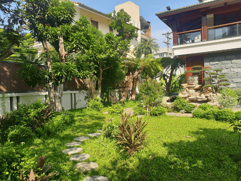 Tiểu cảnh đá xếp tầng đặt gần mặt đứng nhà tạo điểm nhấn vững chãi, hài hòa với mảng tường ốp đá tự nhiên và kiến trúc mái dốc bên trên