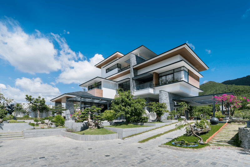 Sân vườn được đầu tư bài bản với bonsai tạo hình, tiểu cảnh đá, thảm cỏ và lối đi lát đá rộng rãi 