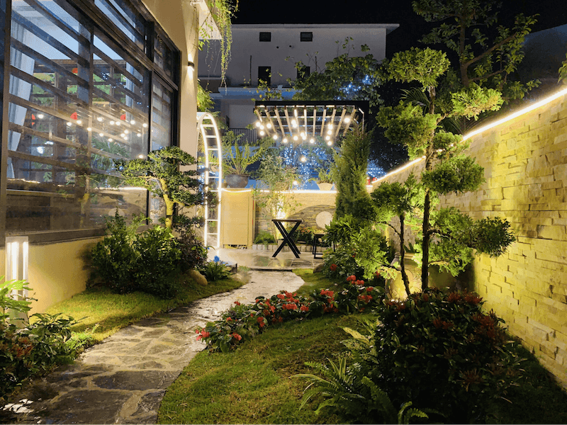 Giàn pergola phía cuối vườn được trang trí bằng chuỗi đèn thả, tạo nên một góc ngồi ấm cúng, lý tưởng cho những buổi trò chuyện hoặc thư giãn sau một ngày dài