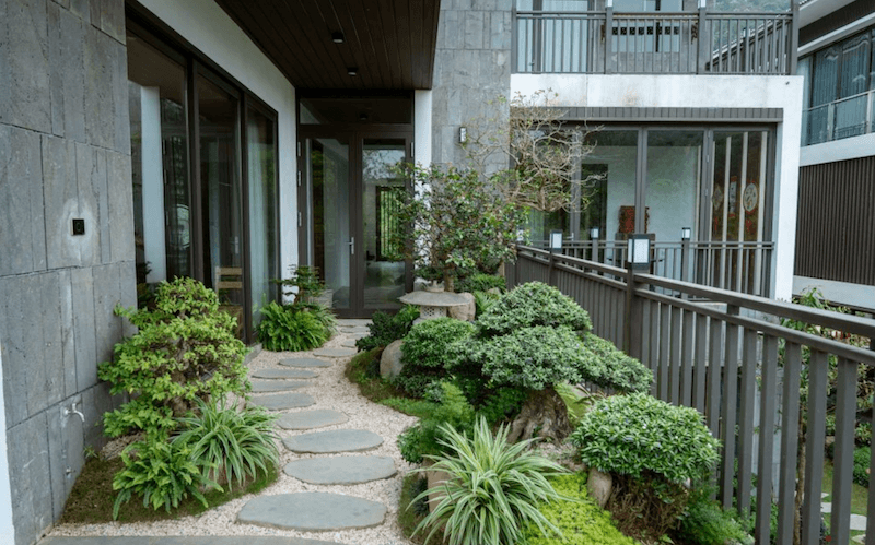 Sự kết hợp giữa đá tự nhiên, sỏi trắng và cây xanh tạo nên bố cục hài hòa, đậm chất Á Đông nhưng vẫn phù hợp với kiến trúc hiện đại của công trình