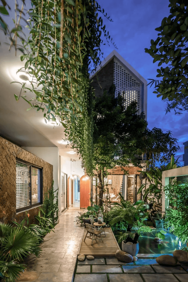 Xung quanh là nhiều loại cây xanh nhiệt đới như cây lá lớn, cây bụi thấp và dây leo rủ từ tầng trên xuống, tạo hiệu ứng “vườn thẳng đứng” mềm mại và sinh động