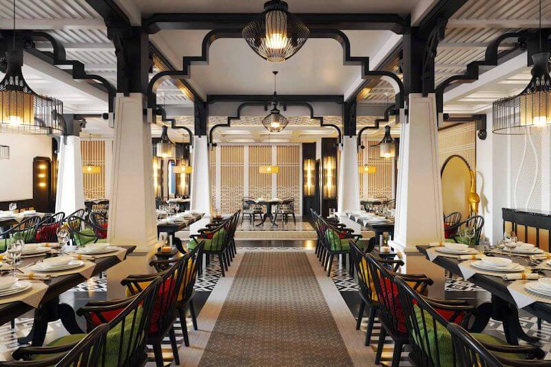 Hệ cột lớn, vòm trang trí màu đen nổi bật trên nền tường sáng cùng gạch bông họa tiết và đèn treo ánh vàng tạo nên cảm giác ấm cúng, tinh tế