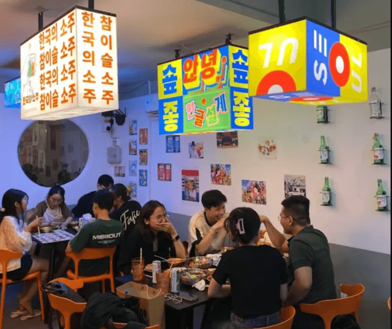 Hệ đèn hộp treo trần với màu sắc vàng - xanh - đỏ cùng typography tiếng Hàn cỡ lớn tạo hiệu ứng thị giác bắt mắt, đúng chất phố đêm Seoul