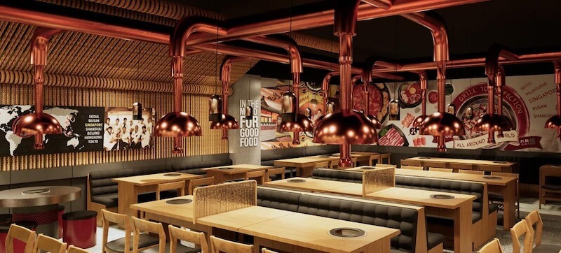 Hệ thống ống hút khói mạ đồng bóng chạy trần như một điểm nhấn thị giác, kết hợp tường graphic ẩm thực và nội thất gỗ sáng màu tạo nên tổng thể cá tính, trẻ trung