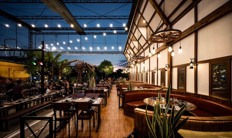 Ánh đèn vàng ấm áp, vật liệu gỗ gần gũi cùng cách bố trí mở tạo nên một bầu không khí vừa sôi động vừa thư giãn