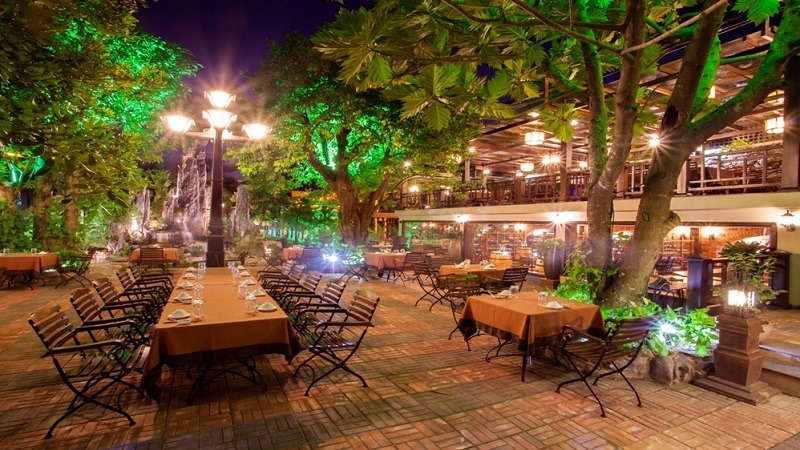 Quán nhậu bình dân không gian mở, khung thép mái che đơn giản, tường gạch thô, bàn ghế gỗ xếp linh hoạt, dễ dọn, phù hợp nhóm đông, ngồi thoải mái