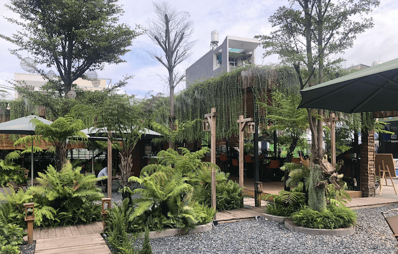 Quán cafe sân vườn nhiệt đới 400m2 được thiết kế xanh mát với nhiều cây lớn, tạo không gian thư giãn gần gũi thiên nhiên cho khách