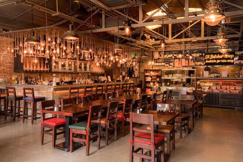 Quán nhậu phong cách Industrial mạnh mẽ với hệ thống đèn thả trần dày đặc, kết hợp nội thất gỗ tối màu tạo không gian sang trọng, ấm cúng