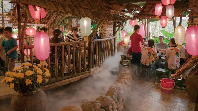 Thiết kế sử dụng khéo léo chất liệu gỗ mộc, mái ngói cũ và bờ đá cuội để tạo nên một không gian ẩm thực bình dị, gần gũi