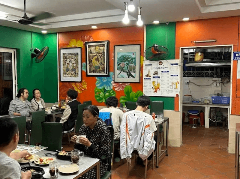 Không gian quán bò bít tết gây ấn tượng với tường sơn màu nổi bật kết hợp tranh trang trí, tạo cảm giác sinh động và gần gũi