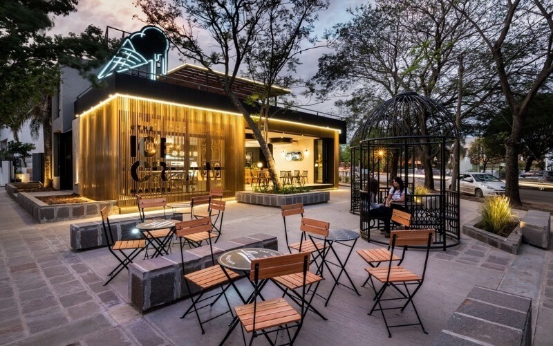 Việc sử dụng bàn ghế gỗ mộc mạc đặt trên sân gạch cùng tiểu cảnh lồng chim độc đáo mang lại không gian thư giãn ngoài trời vô cùng lý tưởng