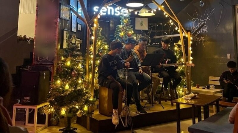 Ánh sáng vàng dịu từ đèn dây và đèn treo giúp không gian buổi tối trở nên ấm áp, phù hợp với không khí acoustic nhẹ nhàng