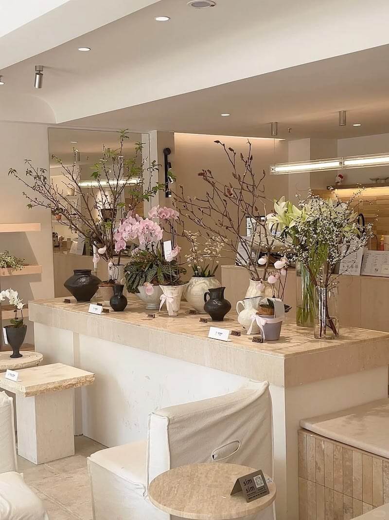 Không gian mang đậm nét tối giản Hàn Quốc với tông kem sữa chủ đạo, kết hợp nội thất đá travertines và những bình hoa tạo hình thanh mảnh, đầy tinh tế