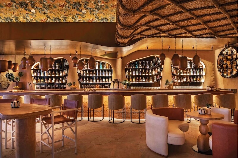 Thiết kế gây ấn tượng với trần đan thủ công uốn lượn, quầy bar bo cong và bảng màu đất ấm, tạo cảm giác mộc mạc nhưng đầy nghệ thuật