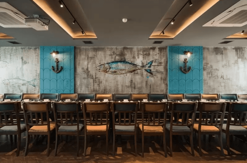 Điểm nhấn của nhà hàng nằm ở bức tường họa tiết đại dương kết hợp biểu tượng mỏ neo, mang đến vẻ sinh động và cá tính riêng